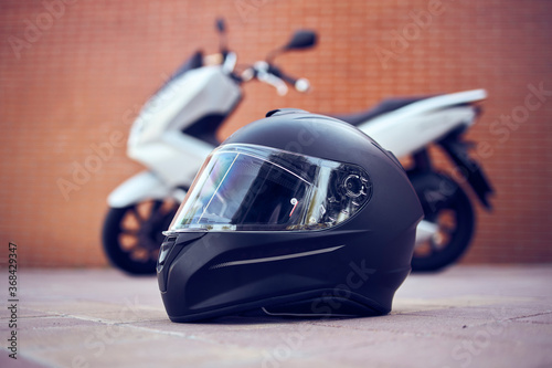 Close-up of a motorcycle black helmet with a white motorcycle in the background. Side view.
