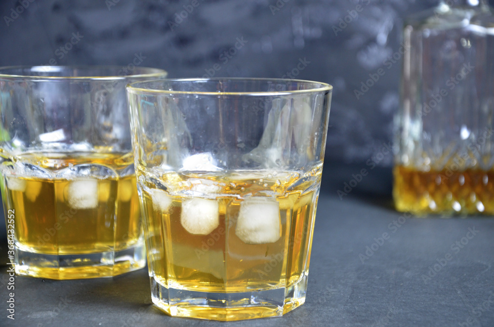 Drink cold tea with ice cubes and mint in two glass goblets a dark black background. Alcoholic or non-alcoholic mahito. whiskey or scotch tape, with lime or lemon Drink cold tea with ice cubes and mint in two glass goblets a dark black background. Alcoholic or non-alcoholic mahito. whiskey or scotch tape, with lime or lemon