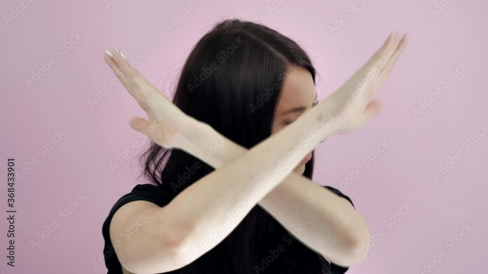 Brunette woman showing signal stop gesture crossed hands over pink background Brunette woman showing signal stop gesture crossed hands over pink background