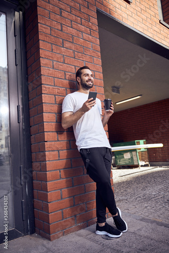 Man with smartphone and coffee outdoor © Yaroslav Astakhov
