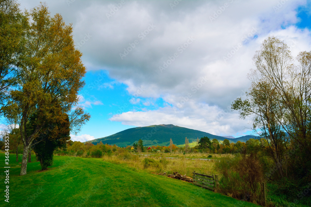 Elevated grass footpath on the banks of Tongariro river leading toward Turangi town and Tongariro National park. Autumn days at North Island, New Zealand