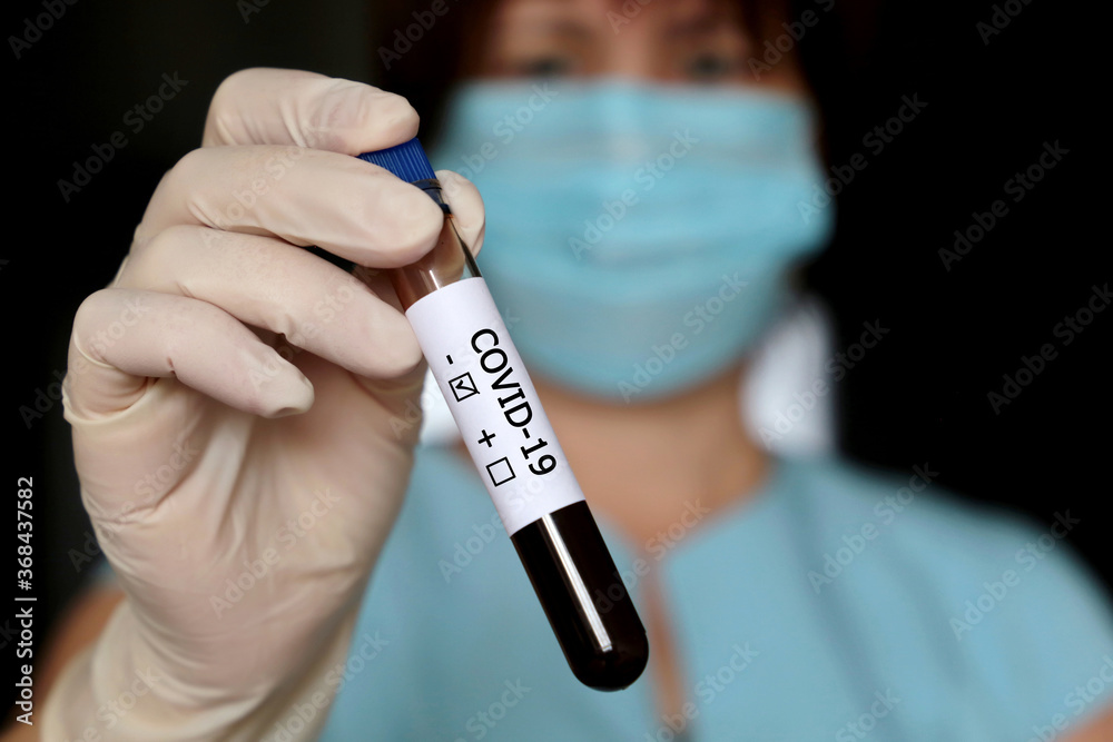 Test tube with covid-19 blood sample in female hands close up, woman in medical mask and gloves holding a vial. Doctor or scientist with negative coronavirus test Test tube with covid-19 blood sample in female hands close up, woman in medical mask and gloves holding a vial. Doctor or scientist with negative coronavirus test