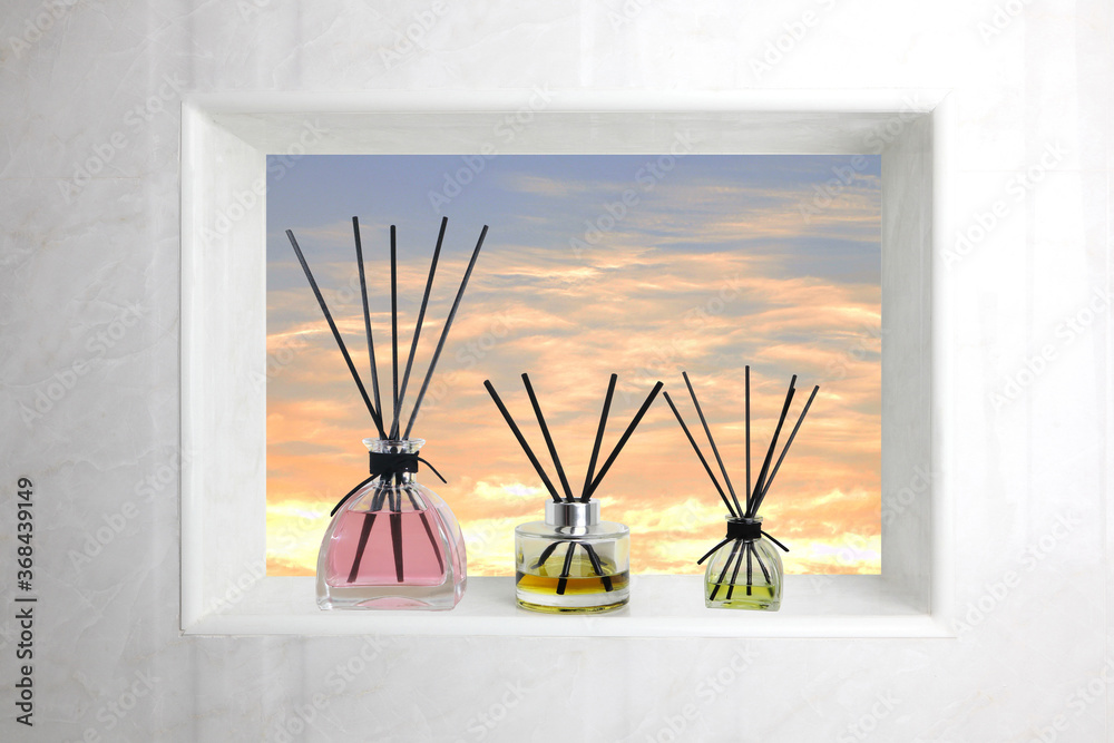 The luxury aroma reed diffuser glass bottle is displayed on the toilet bathroom's window with the view of sun set cloud and twilight sky The luxury aroma reed diffuser glass bottle is displayed on the toilet bathroom's window with the view of sun set cloud and twilight sky
