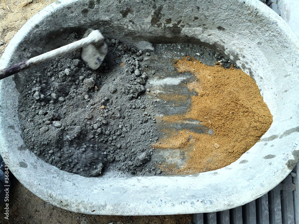 The worker is making cement by mixed sand, rock, and water together in the big bath The worker is making cement by mixed sand, rock, and water together in the big bath