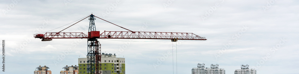 crane of red and blue colours stands among city buildings crane of red and blue colours stands among city buildings