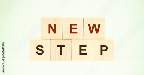 words new step with letters on wooden cubes on light green