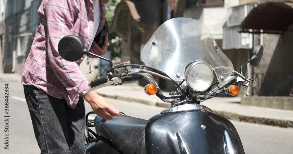 Man inserting key putting on protective helmet and sitting on motorcycle Man inserting key putting on protective helmet and sitting on motorcycle