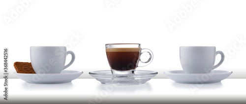 A row of 3 glass and white expresso cups and saucers full of smooth expresso coffee, on a white style bar or table top on white