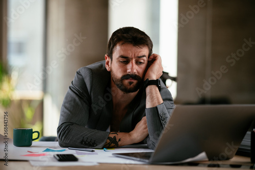 Tired businessman working with laptop at office. Businessman sitting at office desk working on laptop computer..