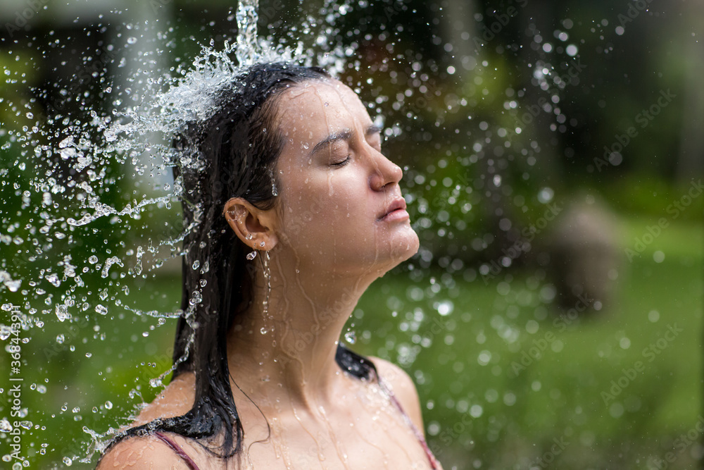 Obraz premium Young slim woman bathing under an outdoor shower. Summer lifestyle