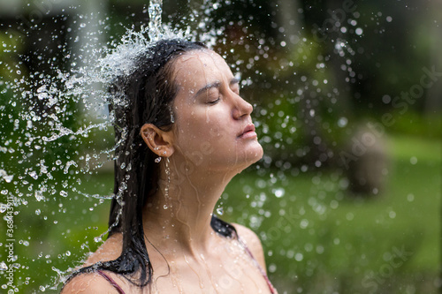 Young slim woman bathing under an outdoor shower. Summer lifestyle