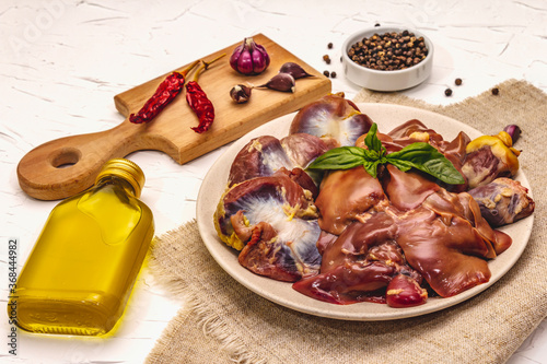 Fresh raw chicken offal: heart, liver, stomach with dry spices, sea salt, chili pepper, olive oil, fresh mint on white putty background photo