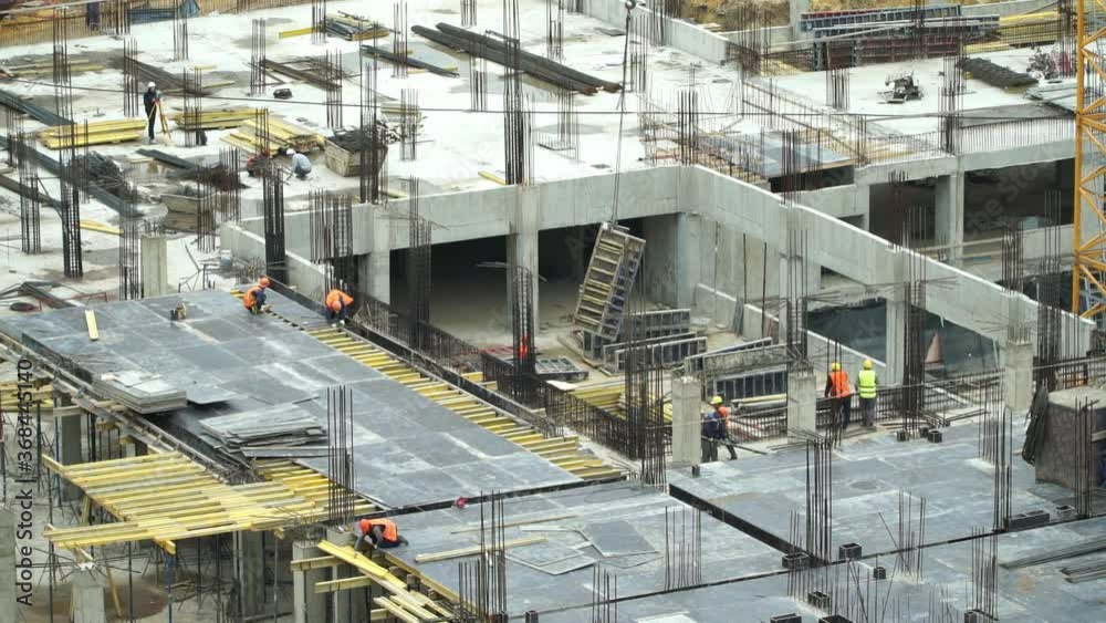Large construction site of residential building with workers. Сonstruction crane lifts support structure. Modern monolithic construction