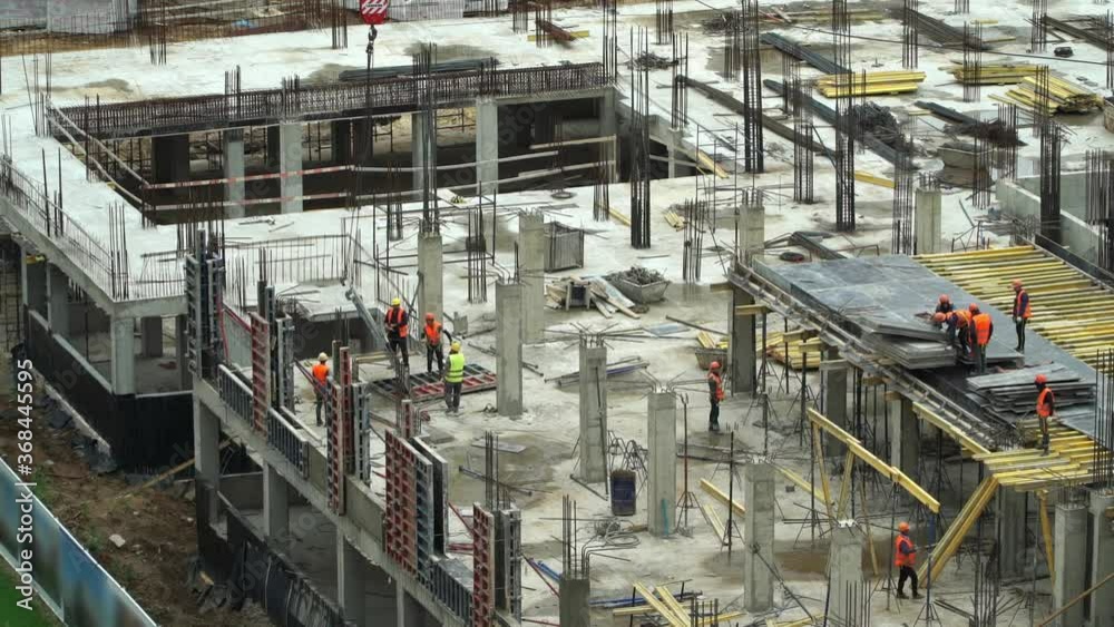 Time lapse construction site of monolithic buildings. Workers work at construction site with crane and reinforced concrete structures. Modern industrial monolithic construction