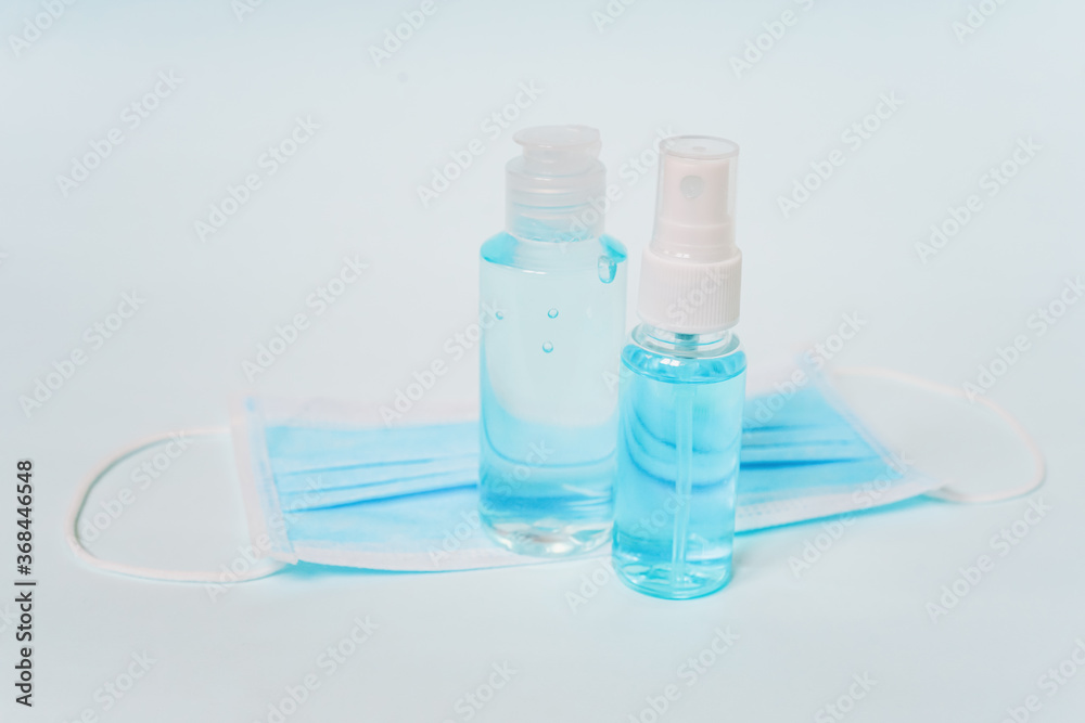 transparent plastic bottle of spray alcohol liquid and gel on blurred surgical mask with light blue background , for new normal concept transparent plastic bottle of spray alcohol liquid and gel on blurred surgical mask with light blue background , for new normal concept