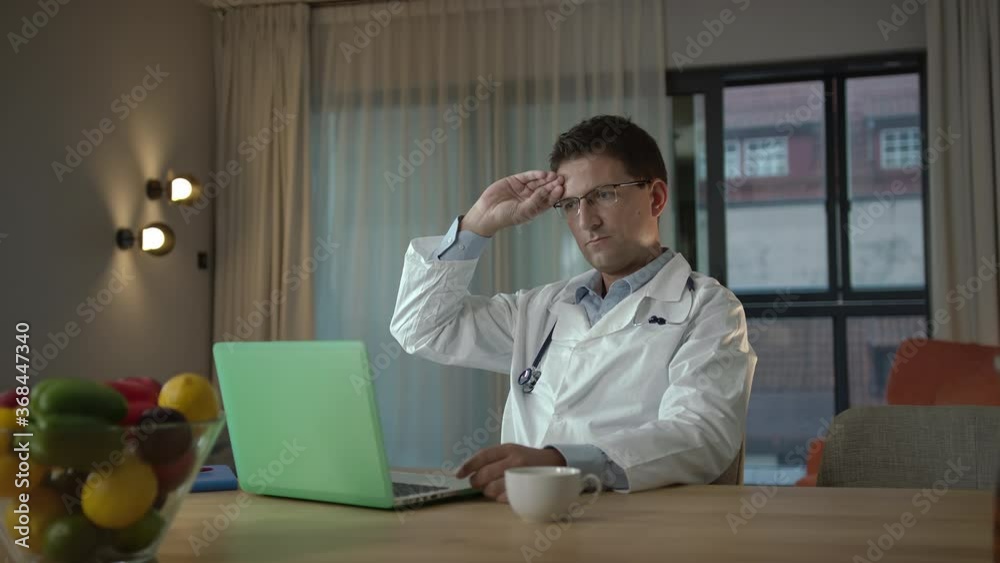 Focused Handsome Caucasian Man Working At Home As A Doctor Giving Online Advices While Videoconferencing In A Modern Apartment Using Her Laptop Focused Handsome Caucasian Man Working At Home As A Doctor Giving Online Advices While Videoconferencing In A Modern Apartment Using Her Laptop