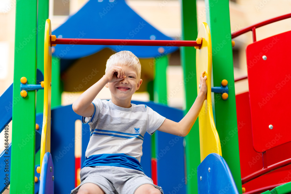 Obraz premium happy baby boy 5-6 years old playing on the Playground in the yard in the summer. Children's lifestyle