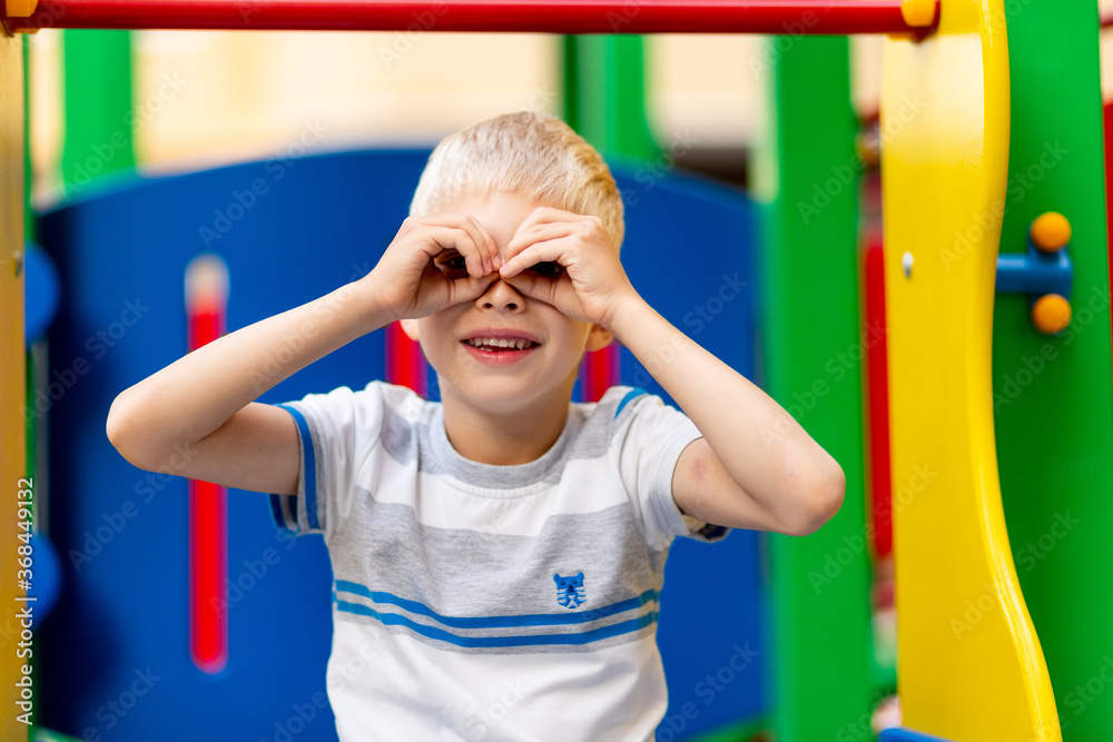 Obraz premium happy baby boy 5-6 years old playing on the Playground in the yard in the summer. Children's lifestyle