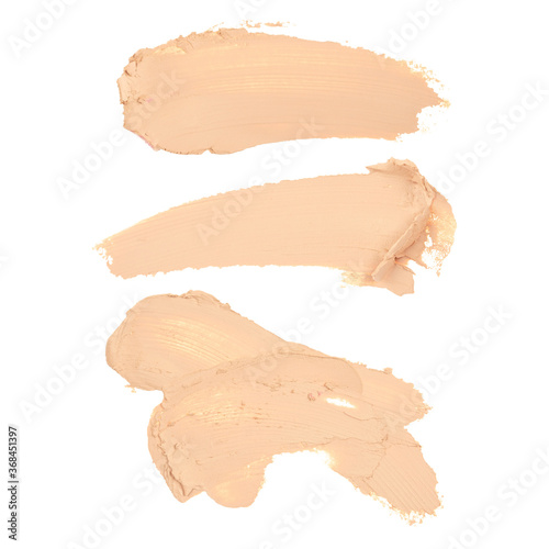 Set of smeared foundation, concealer, makeup base, beige cosmetics of various shapes. Texture, background, template. Broken female makeup isolated on a white background.
