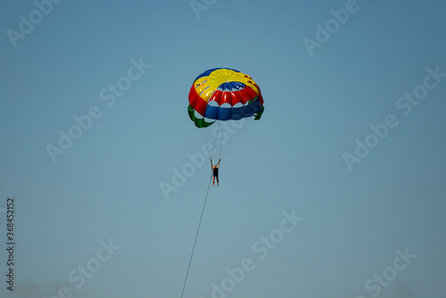 A man on a parachute parachuting over a blue lake.