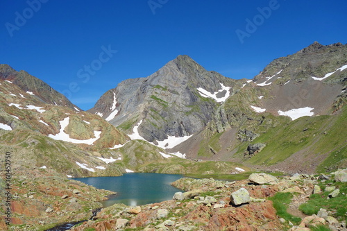 The lower Blue Lake (Ibon Azul), among barren rocky mountains with snow and a blue sky in a sunny autumn, in Panticosa, Aragon Pyrenees
