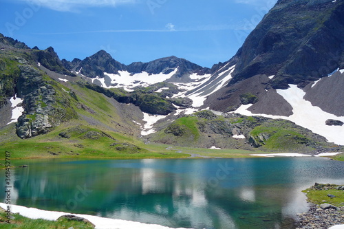 Fototapeta Naklejka Na Ścianę i Meble -  Llena Cantal lake (Ibón de Llena Cantal), among barren rocky mountains with snow and blue sky in a sunny summer in Panticosa, Aragon Pyrenees