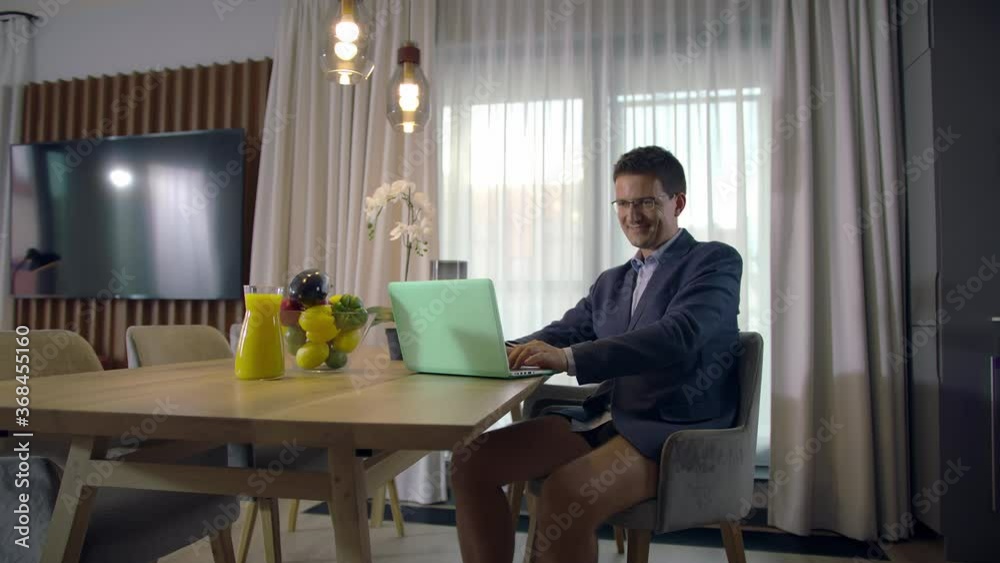 Slow-mo: Focused Handsome Caucasian Man Dressed in a Jacket and Underwear Videoconferencing At Home In A Modern Apartment Using His Laptop Slow-mo: Focused Handsome Caucasian Man Dressed in a Jacket and Underwear Videoconferencing At Home In A Modern Apartment Using His Laptop