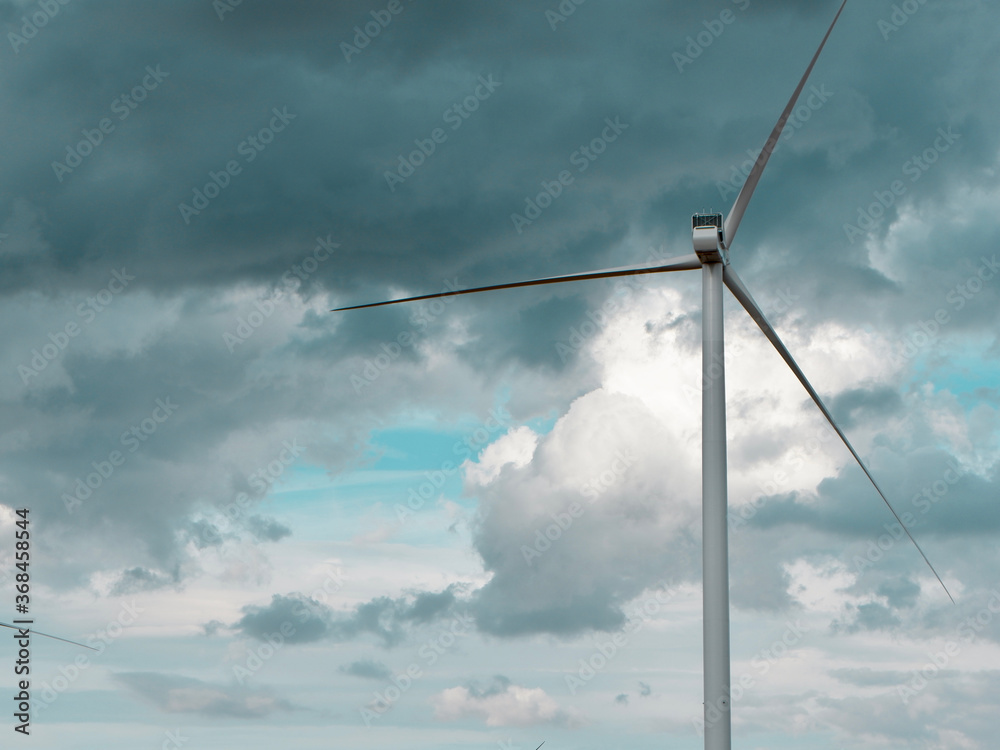 Wind turbine power station against dramatic cloudscape. Environmental background
