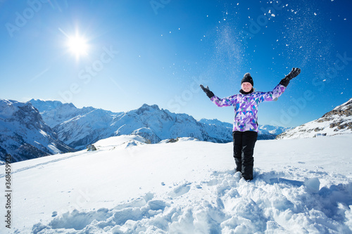 Happy ski girl portrait throw snow in the air standing over mountain top range view