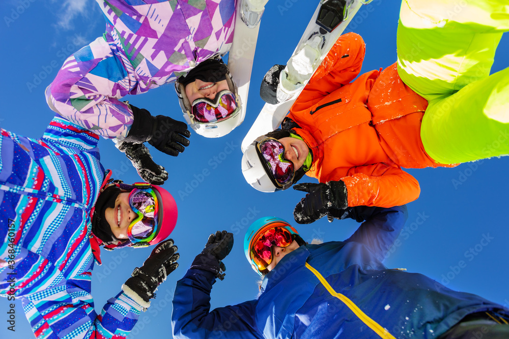 Four teenage girls look down with ski and winter sport outfit standing together smiling