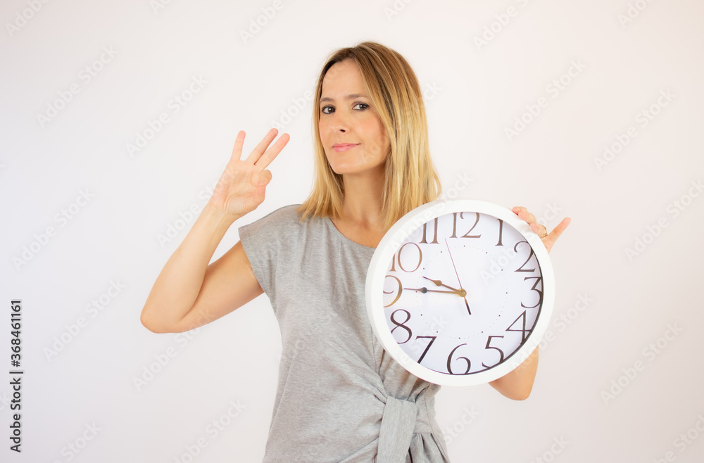 Beautiful woman in grey dress showing a clock Beautiful woman in grey dress showing a clock