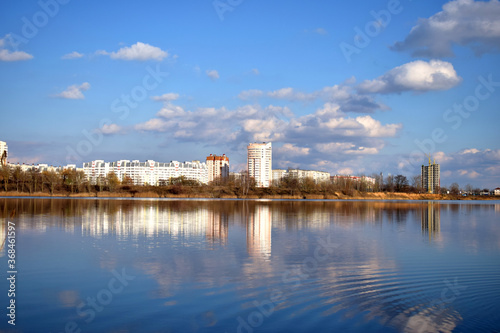on the shore of the lake is a city that is reflected along with the sky and clouds in the water © Ольга Мылица