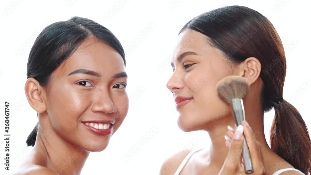 Closeup faces ot two beautiful Asian women smiling, looking at the camera while holding makeup makeup brushes over white background. Natural beauty. Skin care, makeup cosmetics Closeup faces ot two beautiful Asian women smiling, looking at the camera while holding makeup makeup brushes over white background. Natural beauty. Skin care, makeup cosmetics