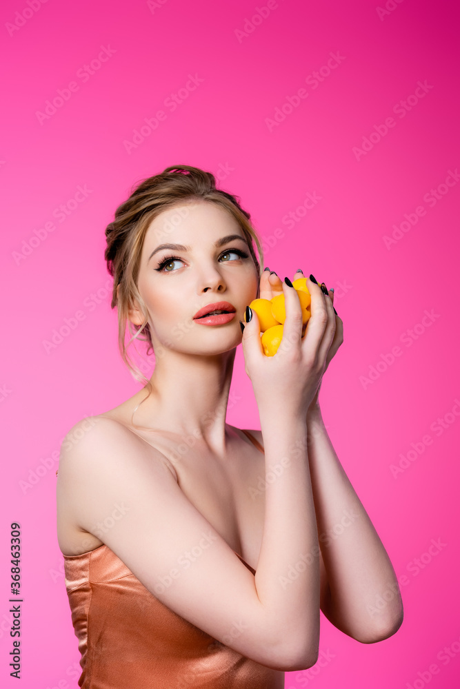 dreamy elegant beautiful blonde woman in silk dress holding ripe apricots isolated on pink