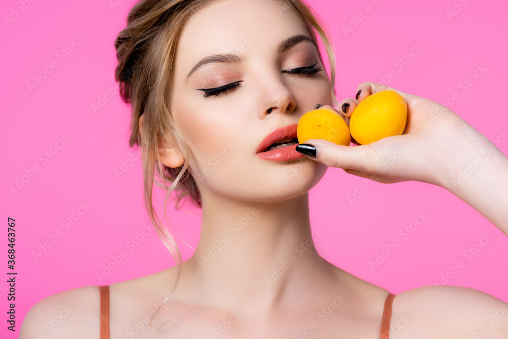 elegant beautiful blonde woman with closed eyes holding apricots isolated on pink elegant beautiful blonde woman with closed eyes holding apricots isolated on pink