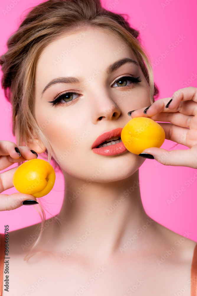 elegant beautiful blonde woman holding apricots isolated on pink elegant beautiful blonde woman holding apricots isolated on pink