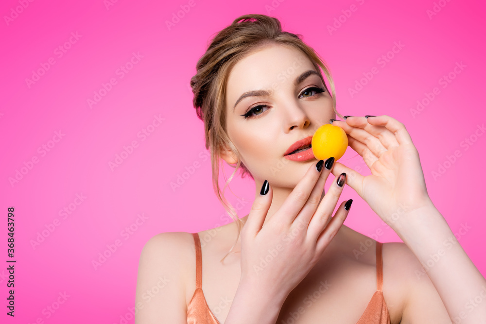 elegant beautiful blonde woman in silk dress holding apricot isolated on pink elegant beautiful blonde woman in silk dress holding apricot isolated on pink