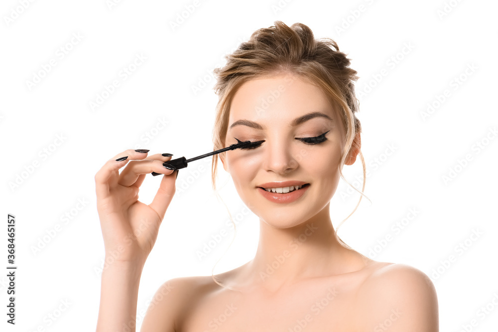 smiling naked beautiful blonde woman with makeup and black nails applying mascara isolated on white