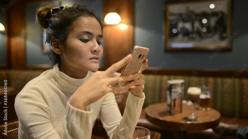 Portrait of young beautiful Asian tourist woman relaxing at the pub indoors Portrait of young beautiful Asian tourist woman relaxing at the pub indoors