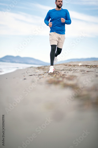 .To Be Young exercise. Healthy active runner running on beach. © luckybusiness