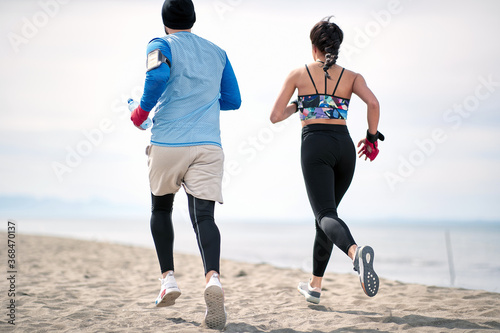 Fitness man and woman  running along beach. photo