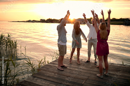 Friends having party at the dock on river at evening.