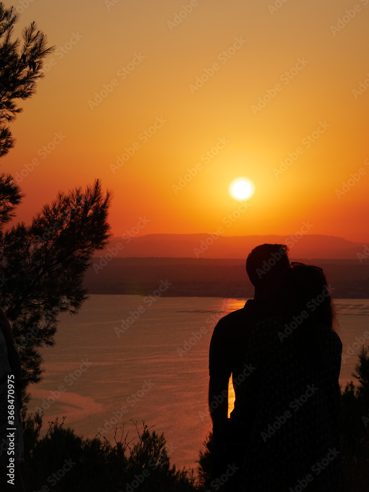 Silhouette of a couple in love watching the sunset