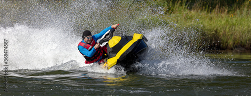 Man on jet ski in the river turns with much splashes
