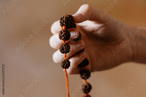Rudraksha beads necklace in female prayer's hand, close up photo