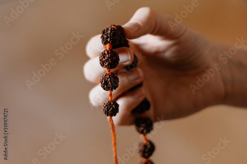 Rudraksha beads necklace in female prayer's hand, close up