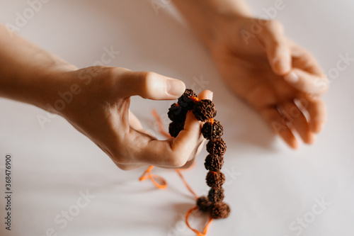 Rudraksha beads necklace in female prayer's hand, close up
