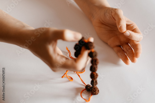 Rudraksha beads necklace in female prayer's hand, close up