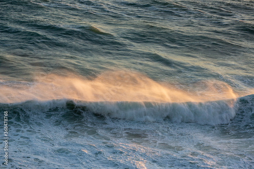  Wind blowing wave in ocean at sunset.