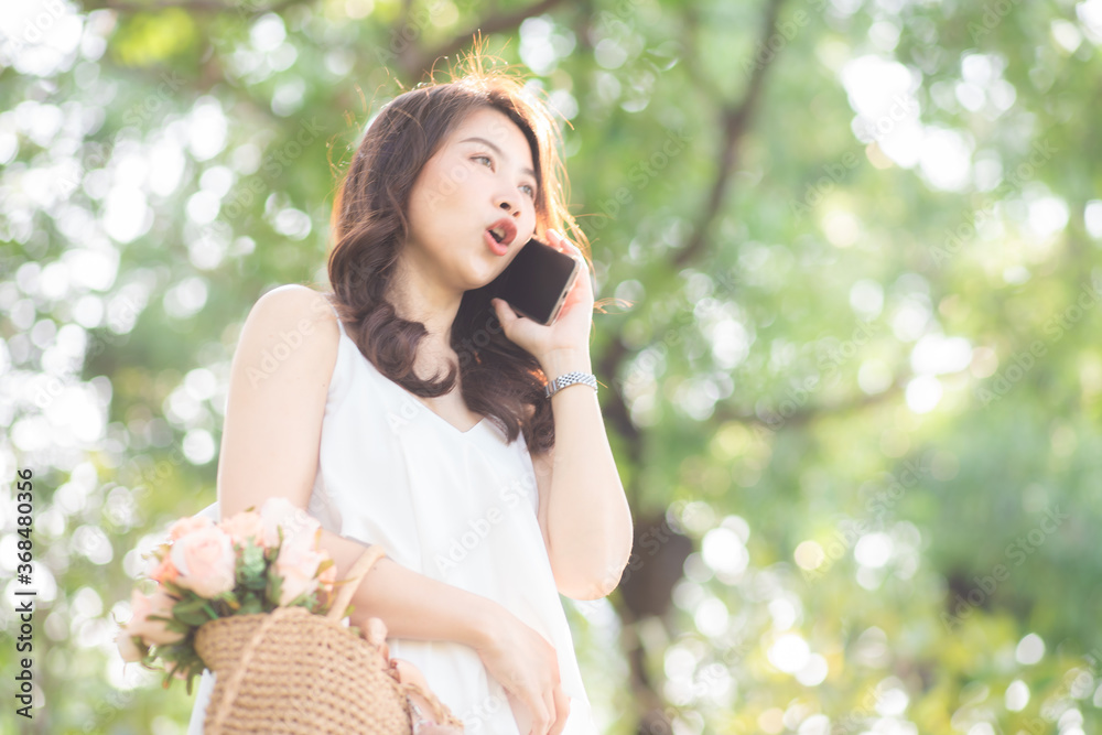 Cheerful young woman talking smartphone in city green park Cheerful young woman talking smartphone in city green park